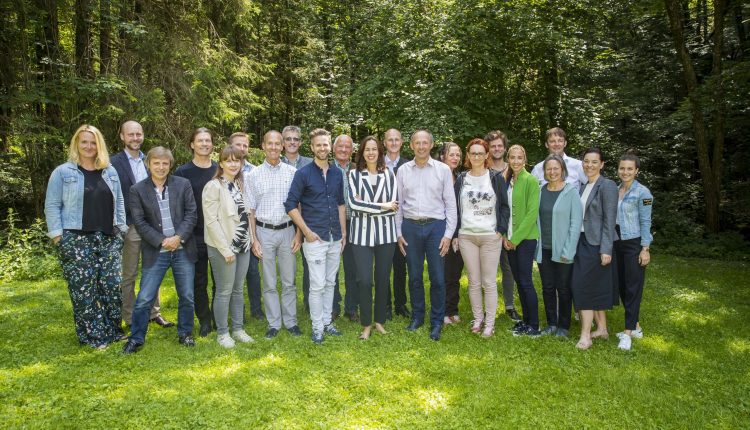 Eine Gruppe von Menschen steht zusammen und lächelt in einem üppigen, grünen Wald.
