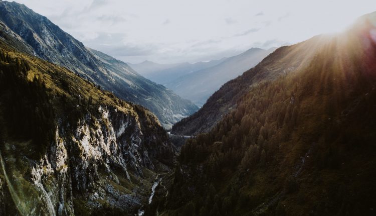 Ein sonnenbeschienenes Gebirgstal, das sich durch bewaldete Hänge schlängelt - perfekt, um neue Reisetrends zu entdecken.