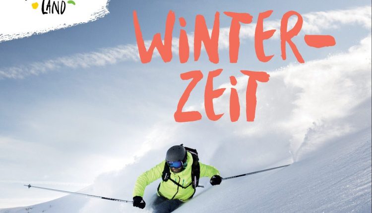 Ein Skifahrer in heller Kleidung carvt durch frischen Pulverschnee unter blauem Himmel, wobei das Logo von Winterzeit und Salzburger Land zu sehen ist.