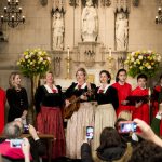 Ein Chor und Musiker treten in einer Kirche auf, während die Zuhörer Fotos mit ihren Handys machen.
