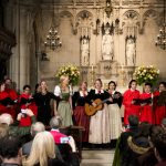 Ein Chor tritt in einer Kirche auf, während die Zuhörer Fotos und Videos von der Veranstaltung machen.