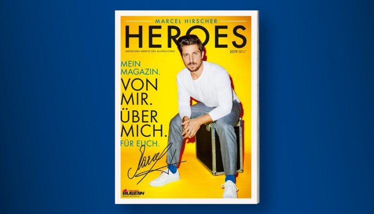 Ein Mann in einem weißen Hemd und einer grauen Hose sitzt auf einer Kiste vor einem gelben Hintergrund auf einem Zeitschriftencover.