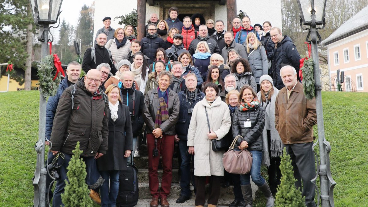 Eine große Gruppe von Menschen posiert an einem bewölkten Tag auf einer Treppe im Freien und lächelt für ein Gruppenfoto.