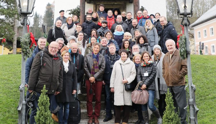 Eine große Gruppe von Menschen posiert an einem bewölkten Tag auf einer Treppe im Freien und lächelt für ein Gruppenfoto.