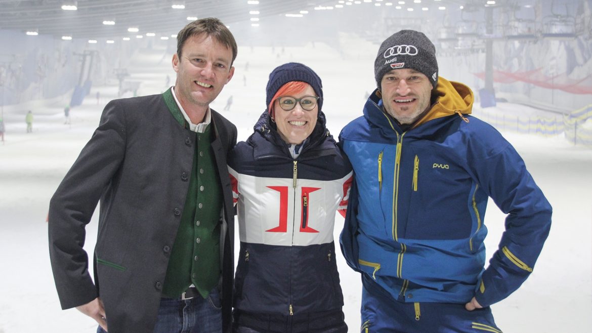 Drei Personen in Winterkleidung lächeln gemeinsam auf einer Skipiste.