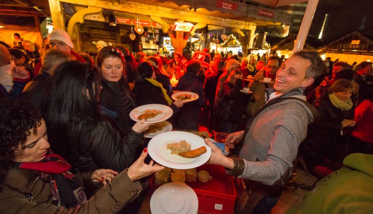 Menschen versammeln sich an einem belebten Essensstand und nehmen auf einem lebhaften Nachtmarkt im Freien Teller mit Essen entgegen.