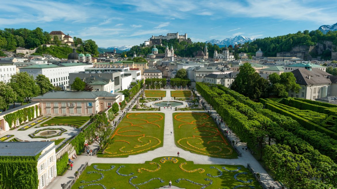 Luftaufnahme des Mirabellgartens in Salzburg, Österreich, mit der Festung Hohensalzburg im Hintergrund.