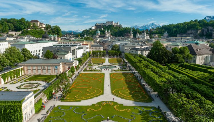 Luftaufnahme des Mirabellgartens in Salzburg, Österreich, mit der Festung Hohensalzburg im Hintergrund.