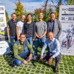 Sieben Personen posieren im Freien zwischen zwei Plakaten für die UCI Mountainbike-Weltmeisterschaften 2020 in Leogang.