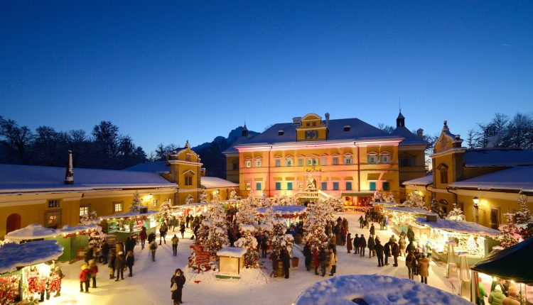 Ein festlicher Weihnachtsmarkt bei Nacht mit bunten Lichtern, geschmückten Ständen und Menschen, die im Schnee spazieren gehen.
