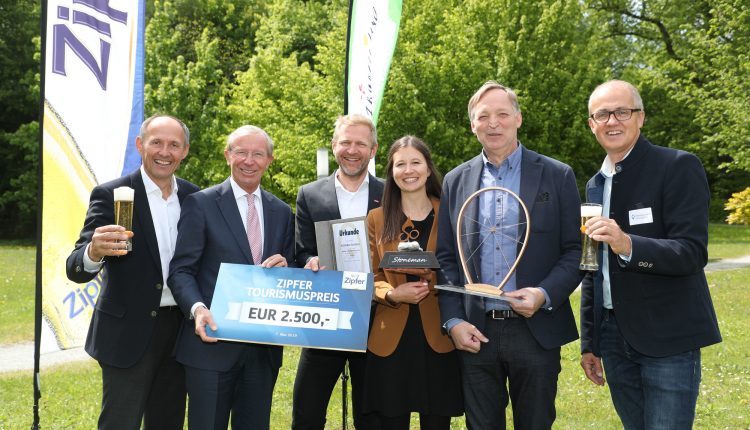 Sechs lächelnde Menschen halten eine Trophäe, ein Preisschild und Getränke bei einer Veranstaltung zur Verleihung des Outdoor-Tourismuspreises.