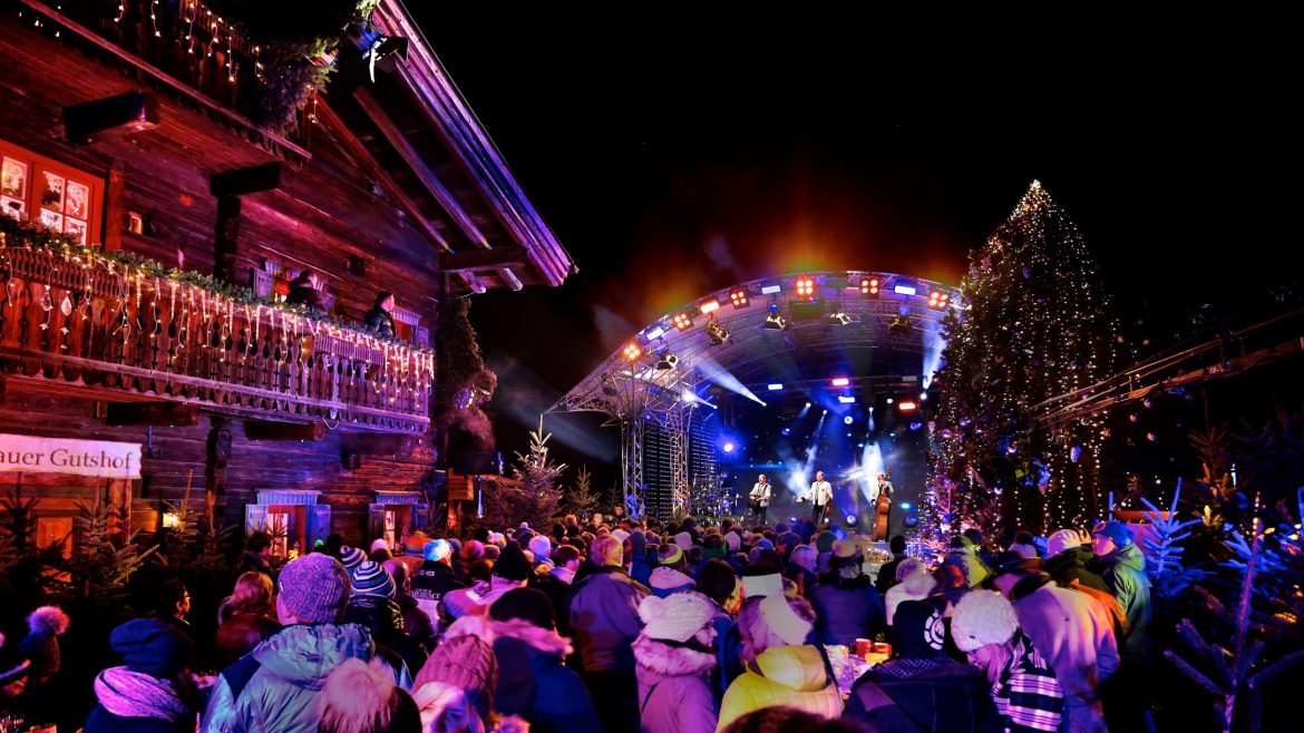 Eine festliche Menschenmenge genießt ein lebhaftes nächtliches Konzert im Freien, umgeben von Lichtern und geschmückten Gebäuden.