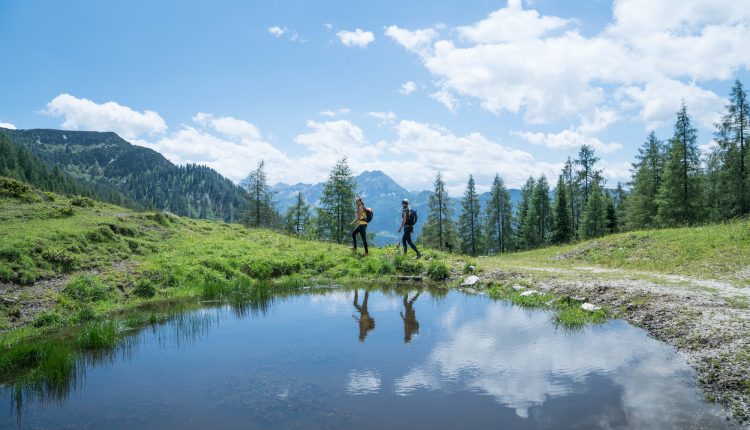 zwei Frauen (beide um die 30 Jahre alt) spiegeln sich in den Lacken des Lackenkogels.
