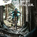 Ein Mountainbiker fährt bergab auf einem von Bäumen gesäumten Waldweg in Salzburg, Österreich.