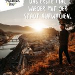 Mann mit Kamera überblickt die Stadt Salzburg bei Sonnenaufgang, mit Text, der in deutscher Sprache für den Tourismus im Salzburger Land wirbt.