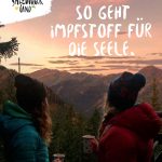 Zwei Personen in Winterkleidung genießen heiße Getränke mit Blick auf die Berglandschaft bei Sonnenuntergang im Salzburger Land.