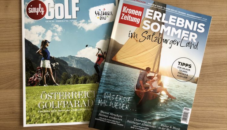 Zwei Zeitschriften auf einem Tisch: eine über Golf in Österreich, die andere über Sommererlebnisse im Salzburger Land.