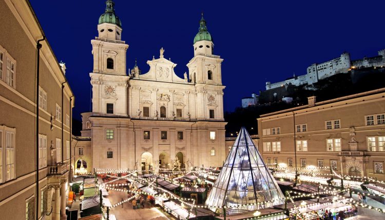 Salzburger Dom und Weihnachtsmarkt bei Nacht, mit festlicher Beleuchtung und einer Glaspyramide in der Mitte.