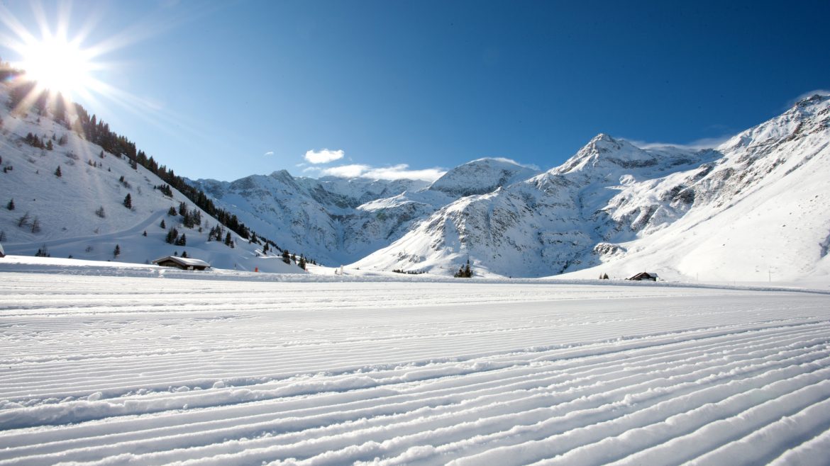 Frisch präparierter Schnee, Sonnenschein über verschneiten Bergen und ein strahlend blauer Himmel.