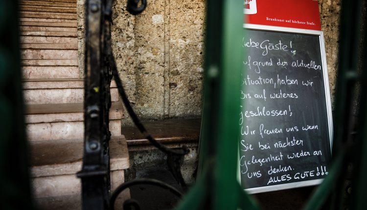 Ein Kreideschild mit handgeschriebenem deutschen Text steht neben einer Steintreppe mit Eisengeländer.
