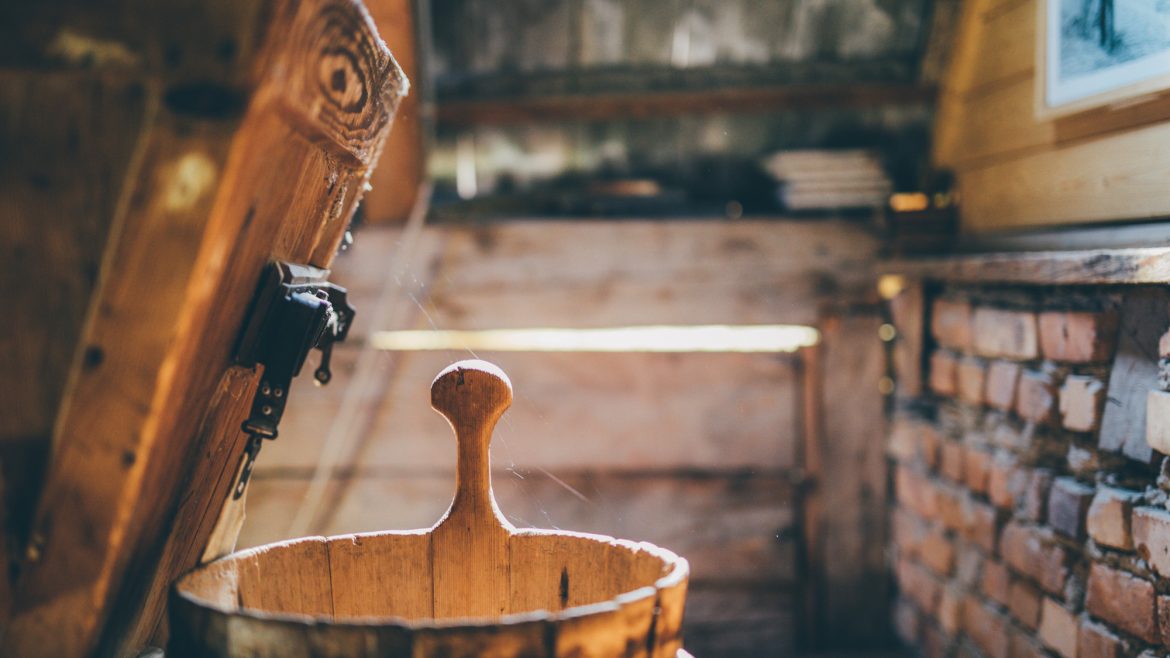 Holzeimer mit Henkel in einer rustikalen, sonnenbeschienenen Hütte mit Holz- und Ziegelwänden.