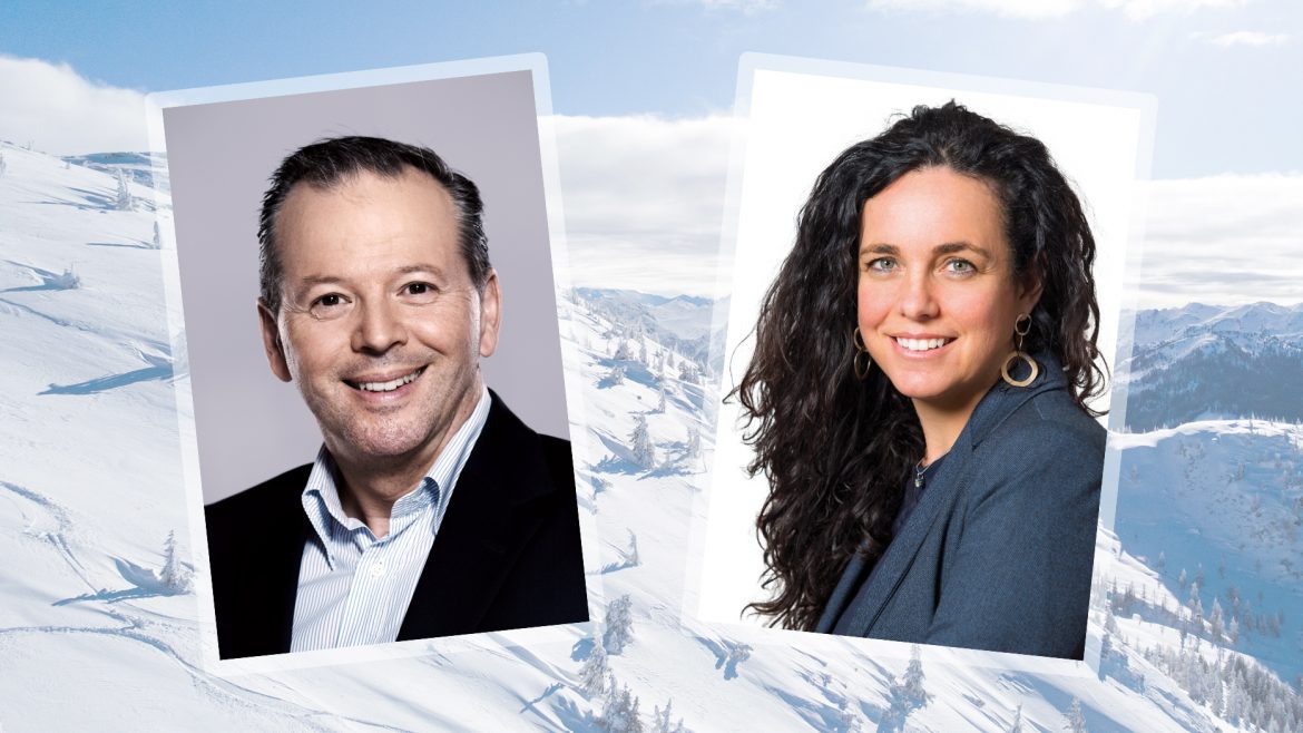 Ein Mann und eine Frau in Geschäftskleidung, lächelnd, vor einem verschneiten Berghintergrund.