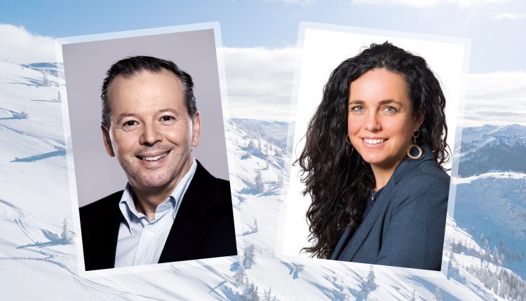 Ein Mann und eine Frau in Geschäftskleidung, lächelnd, vor einem verschneiten Berghintergrund.