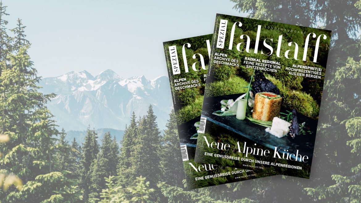 Zwei Falstaff-Magazine mit alpiner Küche vor der Kulisse von Tannen und schneebedeckten Bergen.
