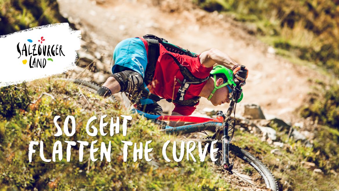 Ein Mountainbiker biegt auf einem felsigen Weg scharf in eine Kurve ein, mit Salzburger Land und Textüberlagerung.