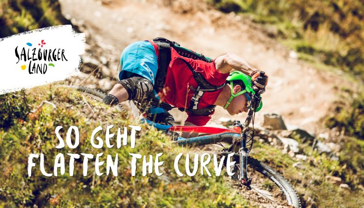 Ein Mountainbiker biegt auf einem felsigen Weg scharf in eine Kurve ein, mit Salzburger Land und Textüberlagerung.