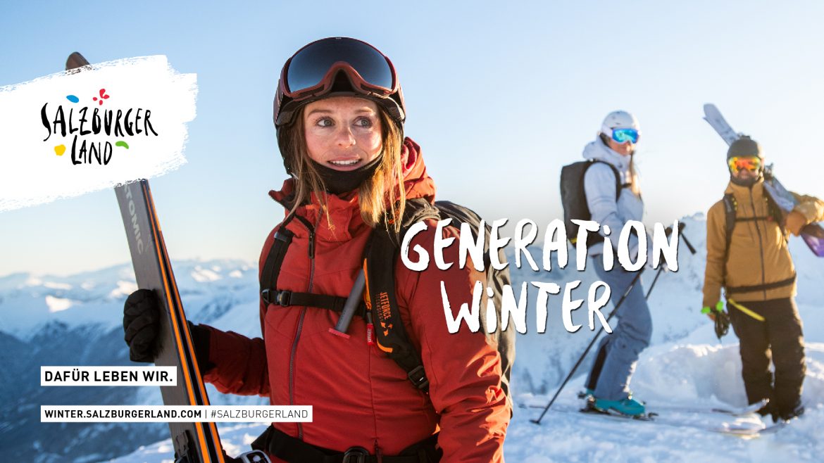 Drei Personen mit Skiern stehen auf einem verschneiten Berggipfel unter strahlend blauem Himmel, gekleidet in Winterkleidung.
