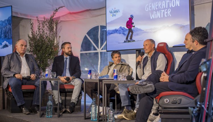 Sechs Männer sitzen auf der Bühne und führen eine Podiumsdiskussion vor zwei Bildschirmen, auf denen "Generation Winter" zu lesen ist.