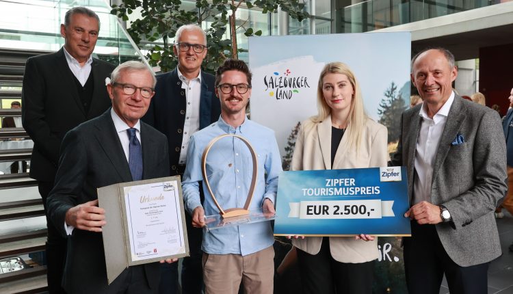 Sechs lächelnde Menschen in einem Raum, die eine Auszeichnung, eine Urkunde und ein Schild mit einem Tourismuspreis von 2 500 € in der Hand halten.