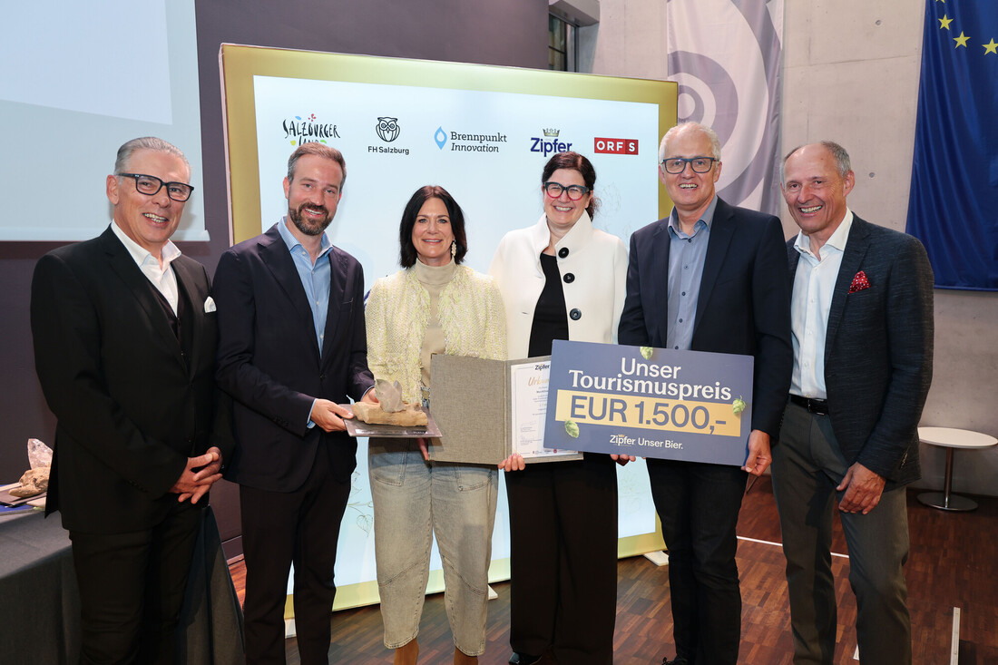 Sechs Personen stehen lächelnd beieinander und halten eine Trophäe, eine Urkunde und ein Schild für einen mit 1 500 Euro dotierten Tourismuspreis in der Hand.