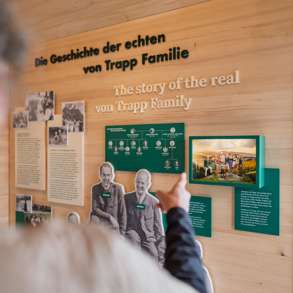 Eine Person zeigt auf eine Ausstellung im Museum über die echte Familie von Trapp, an deren Wänden Texte und Fotos zu sehen sind.