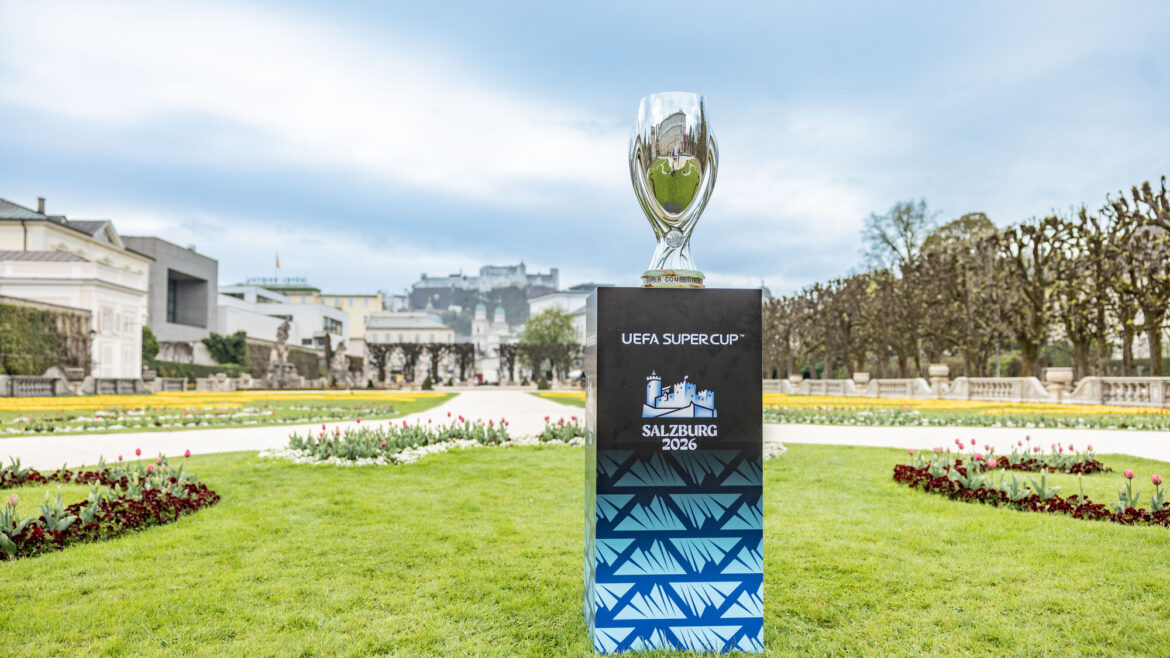 Die Trophäe des UEFA-Supercups auf einem Sockel in einem Garten, auf dem Sockel steht „Salzburg 2026“.