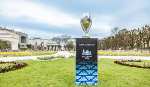 Die Trophäe des UEFA-Supercups auf einem Sockel in einem Garten, auf dem Sockel steht „Salzburg 2026“.