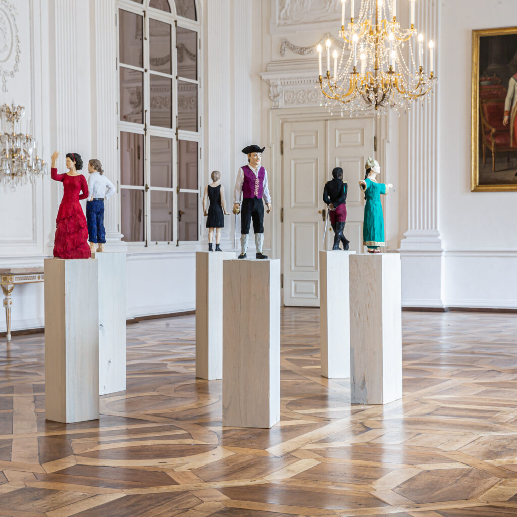 Vier Schaufensterpuppen in historischer Kleidung präsentieren unter funkelnden Kronleuchtern die kulturellen Sommer-Highlights.