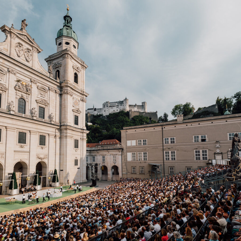 Kulturelle Sommer-Highlights locken zahlreiche Besucher auf einen historischen Platz vor der Kulisse einer Kirche und einer Festung.