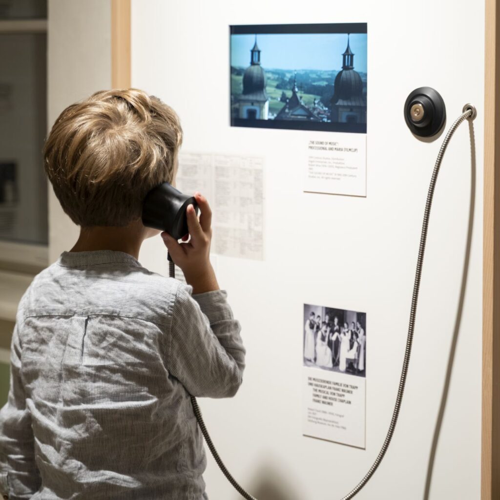 Ein kleiner Junge hört sich ein altmodisches Telefon in der Ausstellung des „Sound of Music“-Museums in Salzburg an.