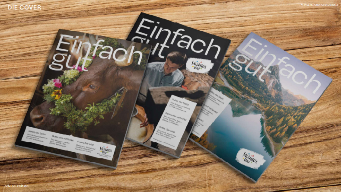 Drei Ausgaben der Zeitschrift „Einfach gut“ auf einem Holztisch, auf deren Titelseiten eine Kuh, ein Koch und ein See abgebildet sind.