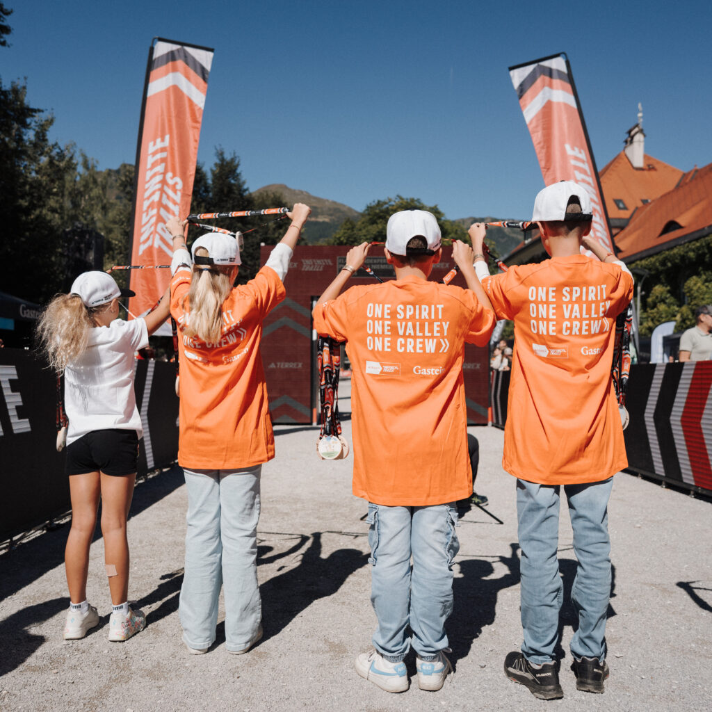 Vier Personen in orangefarbenen Shirts mit Wanderstöcken stehen vor Veranstaltungsbannern – Veranstaltungsrückblick September 2026 im Freien.