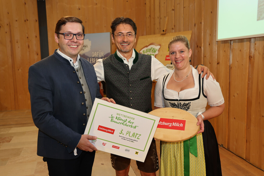 Drei Personen in traditioneller österreichischer Tracht halten eine Urkunde über den dritten Platz bei einem Wettbewerb von SalzburgMilch in den Händen.