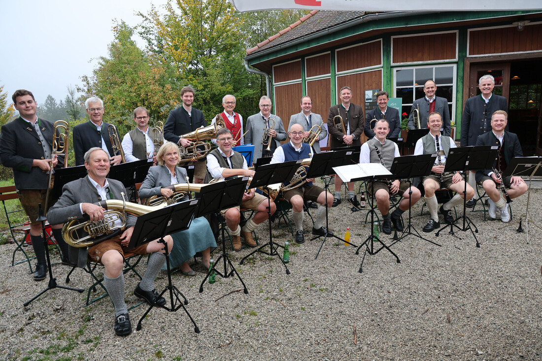 Eine große Blaskapelle in traditioneller österreichischer Tracht posiert mit ihren Instrumenten im Freien.