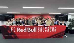 Eine große Gruppe von Menschen, die hinter einem roten Banner mit der Aufschrift FC Red Bull Salzburg für ein Foto posiert.